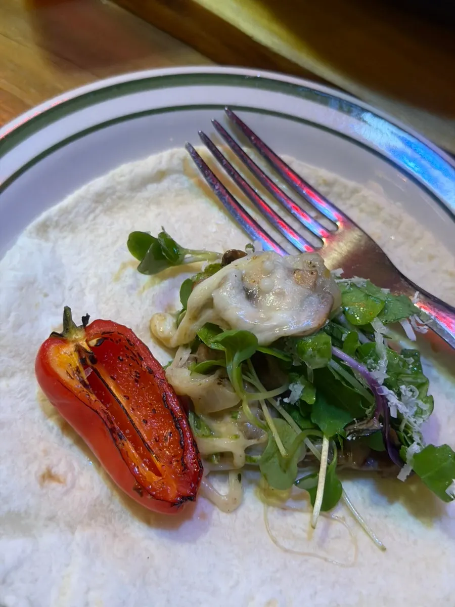 A wrapped bite of taco combining various sauces