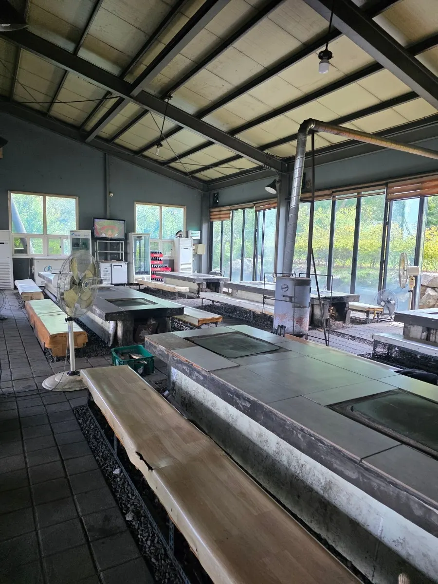 Indoor seating and stone-plate grilling area at Yaksamgol Garden
