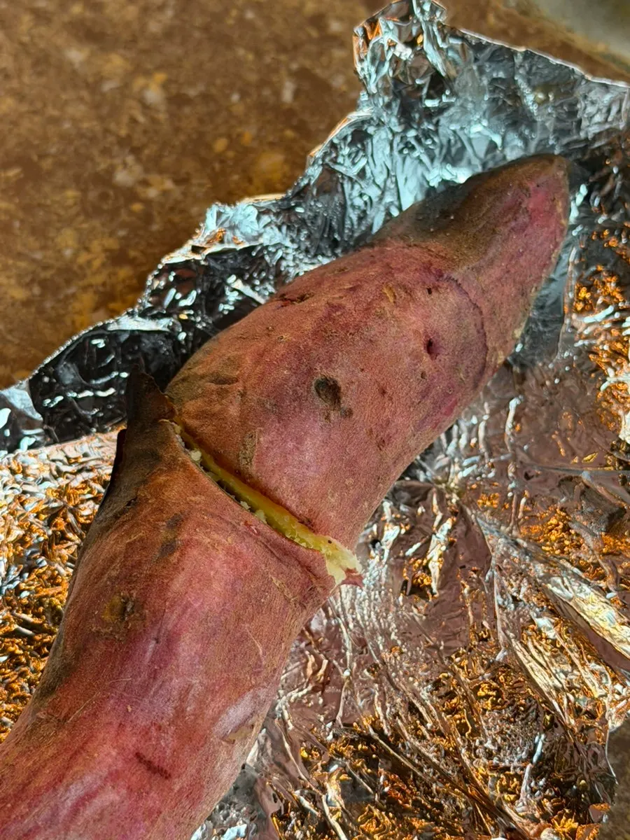 Roasted sweet potatoes cooking in a wood fire