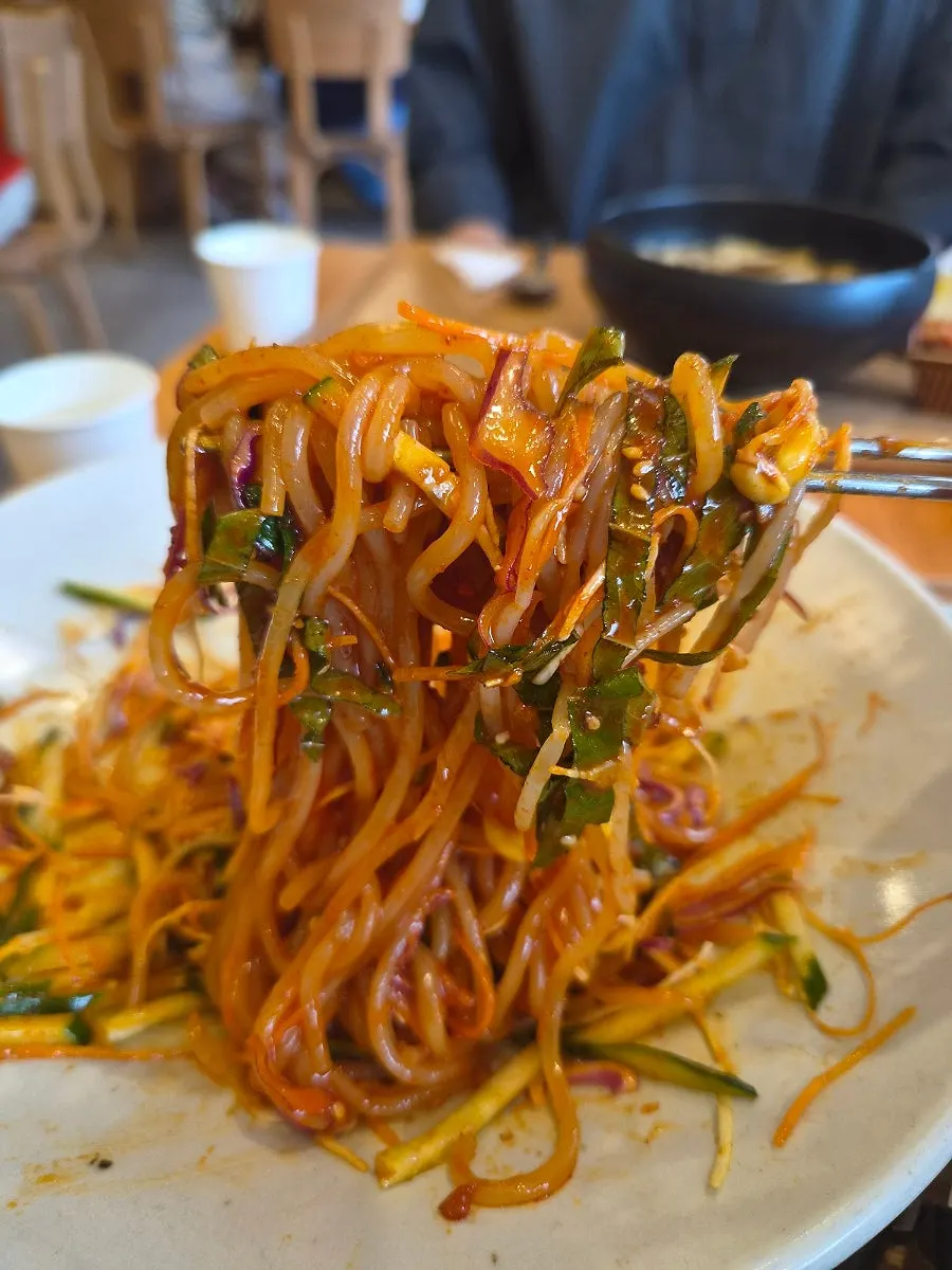 Chewy jjolmyeon noodles lifted with chopsticks