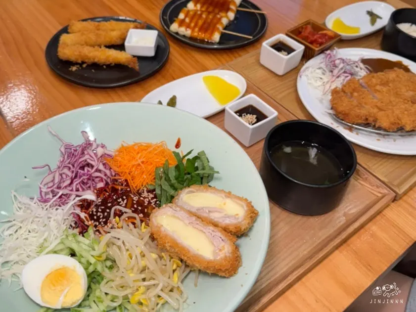 A table spread with jjolmyeon, pork cutlet, and sides