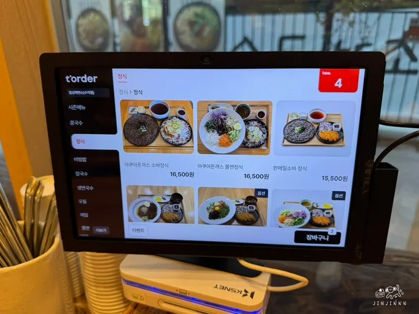 Menu board listing charcoal bibim jjolmyeon and udon
