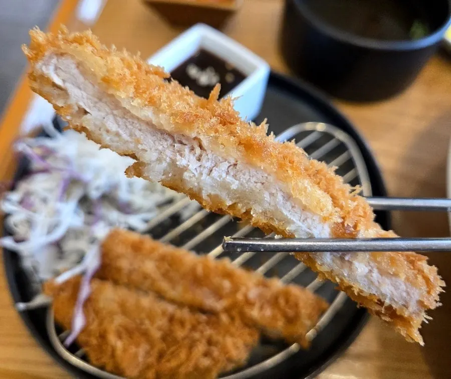 소스에 찍은 바삭한 돈가스 한 조각