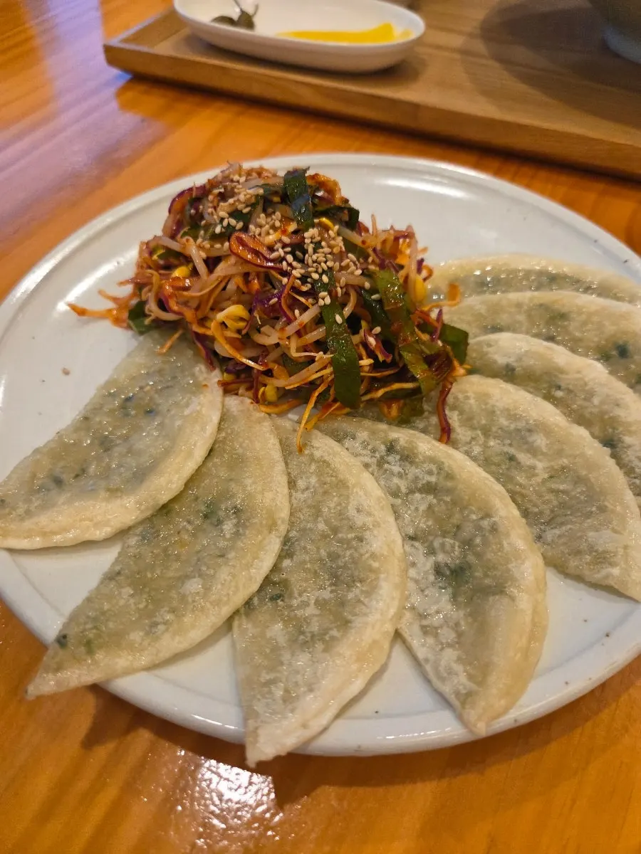 Bibim mandu served with flat dumplings and seasoned vegetables