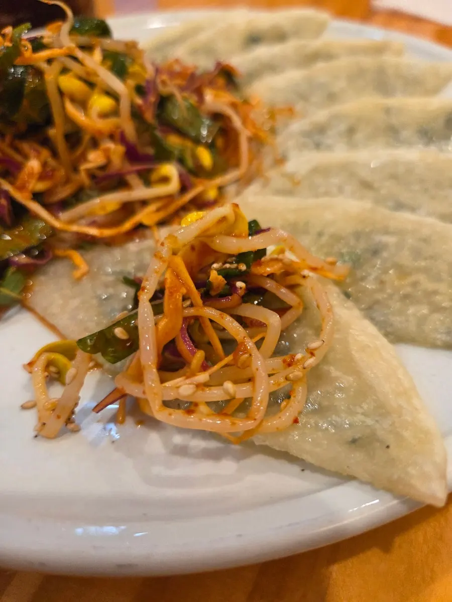 A piece of bibim mandu topped with seasoned vegetables
