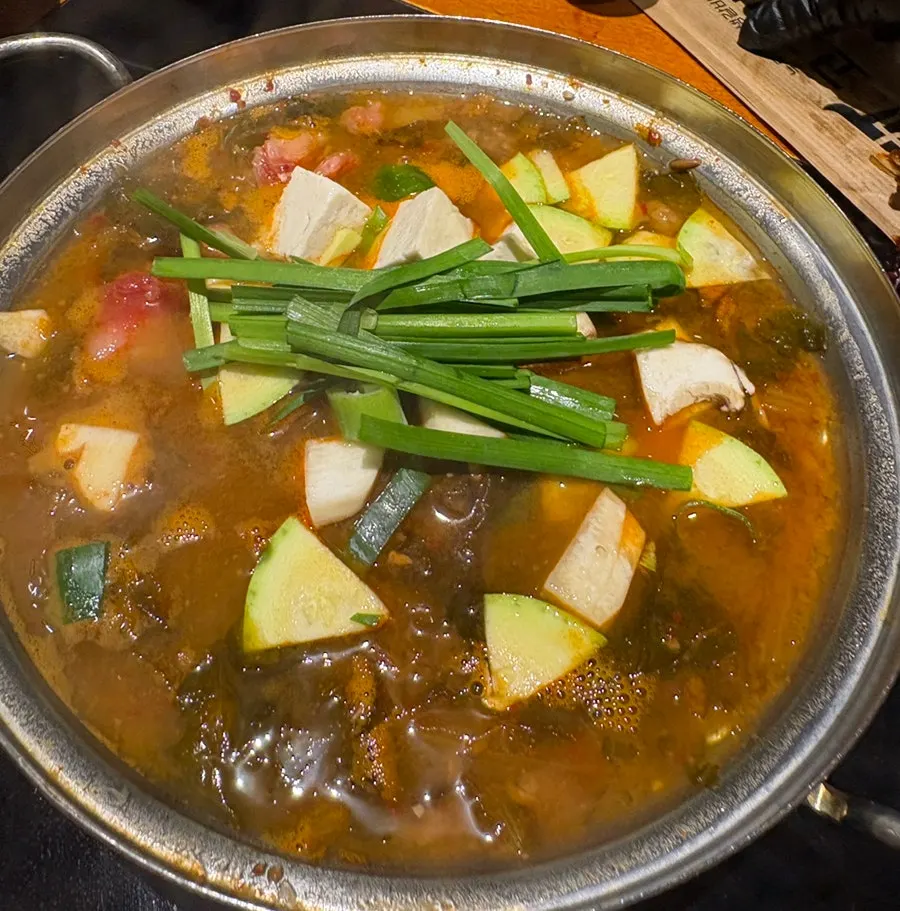 Pork kimchi jjigae simmering beside the grill