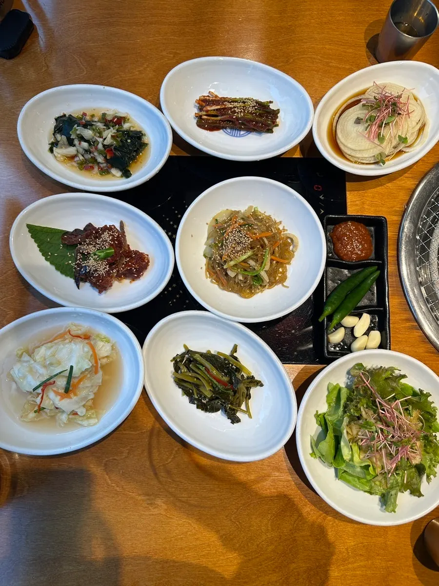 Basic table setting with salad, green onion kimchi, dongchimi, japchae, and yangnyeom gejang
