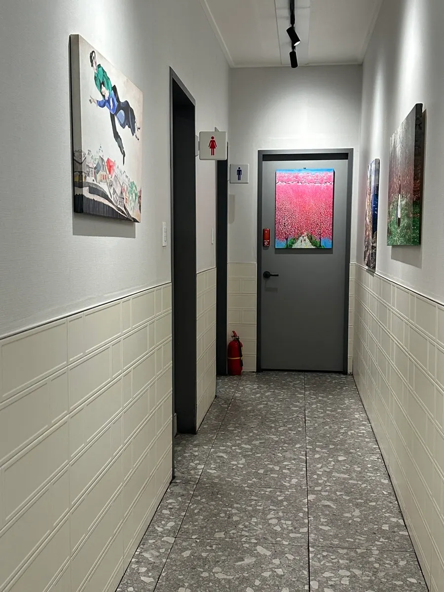 Hallway with paintings leading to the restrooms