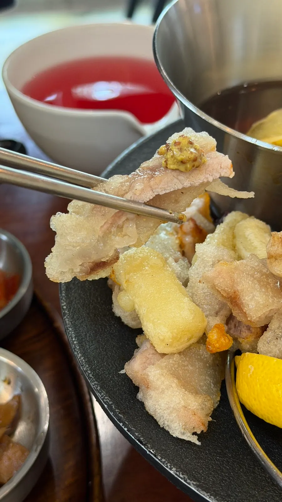 A piece of tangsuyuk dipped in whole grain mustard