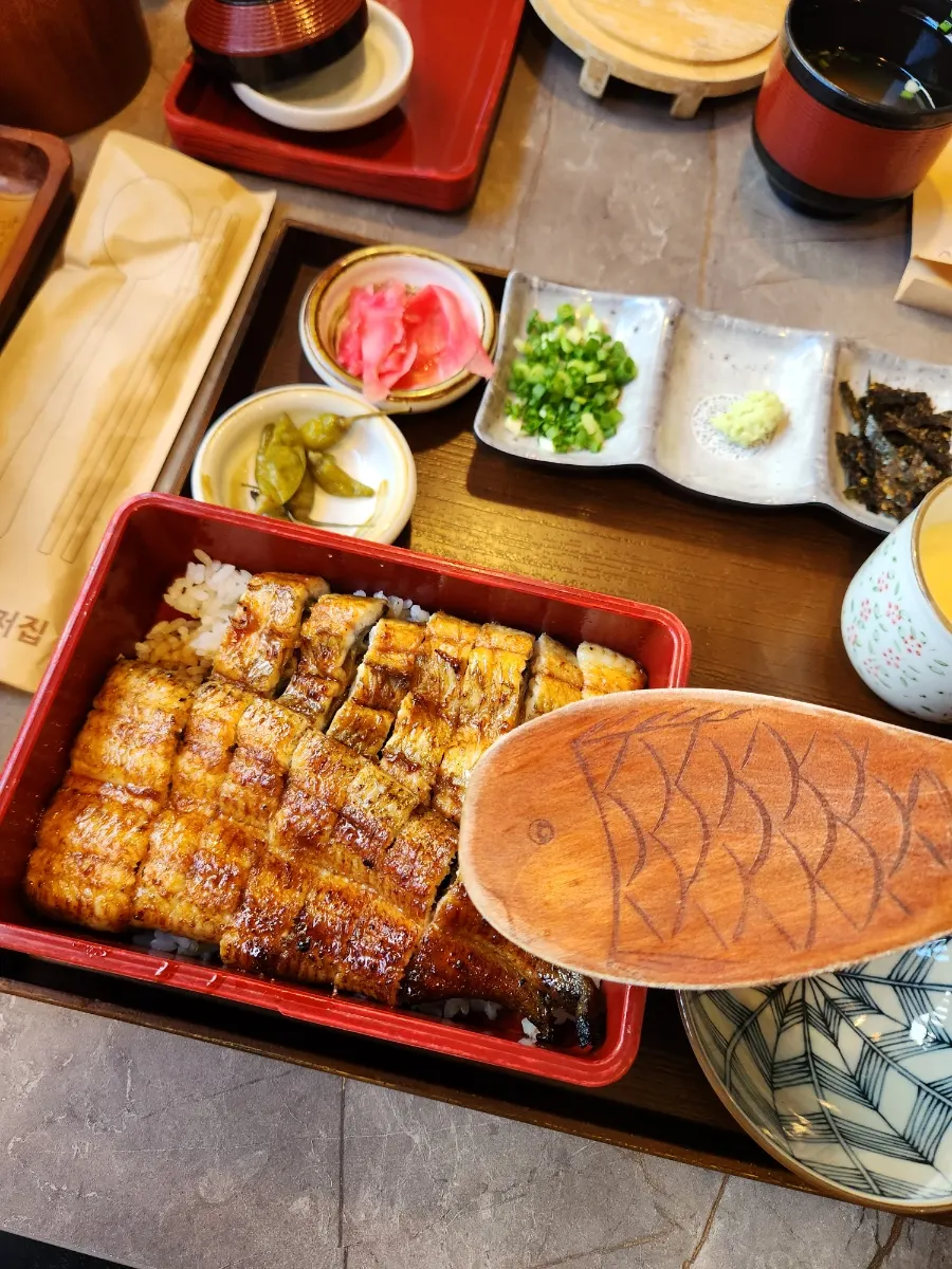 Dividing the eel rice bowl with a fish-shaped paddle