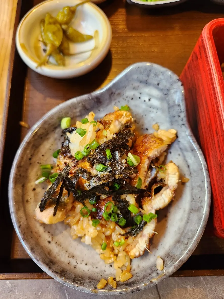 A bowl of rice and eel topped with seaweed and scallion
