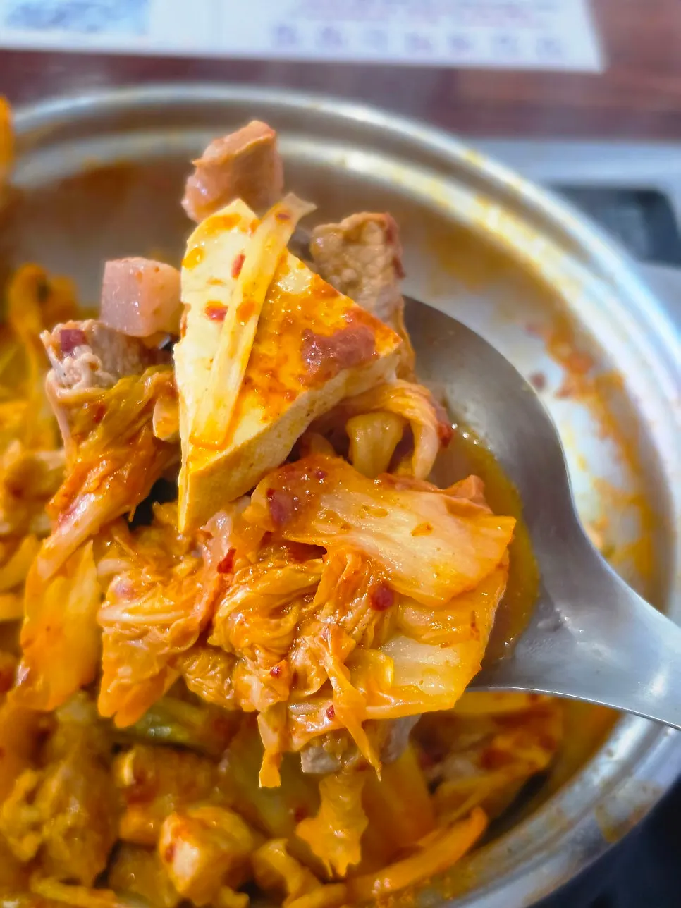 A spoonful of rice topped with kimchi jjigae broth