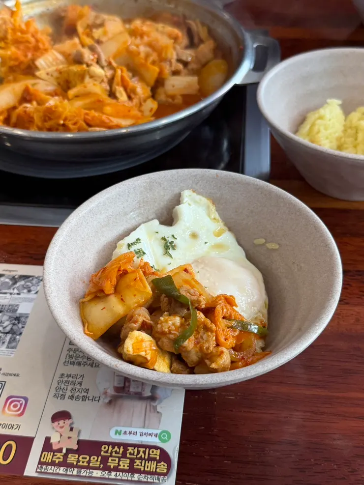 A spoonful of rice topped with kimchi jjigae and runny egg