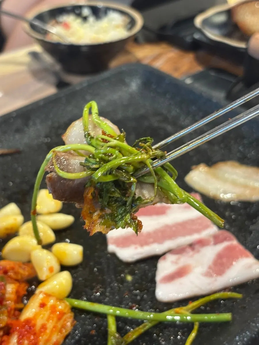 Meat served with grilled kimchi and minari