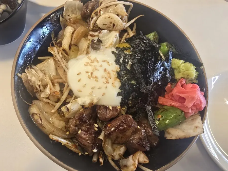 Bowl of cube steak rice bowl topped with egg and vegetables