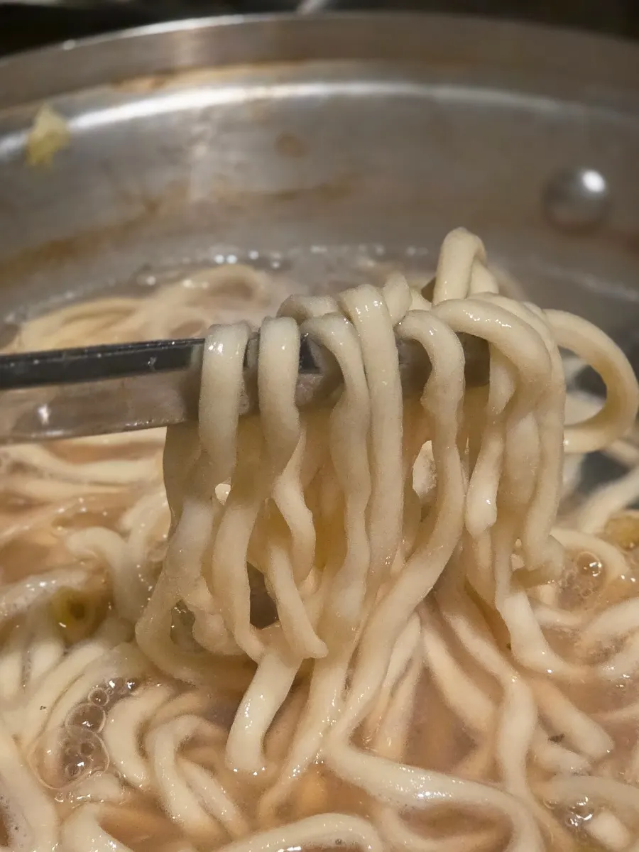 在海鲜汤里放入面条煮的样子