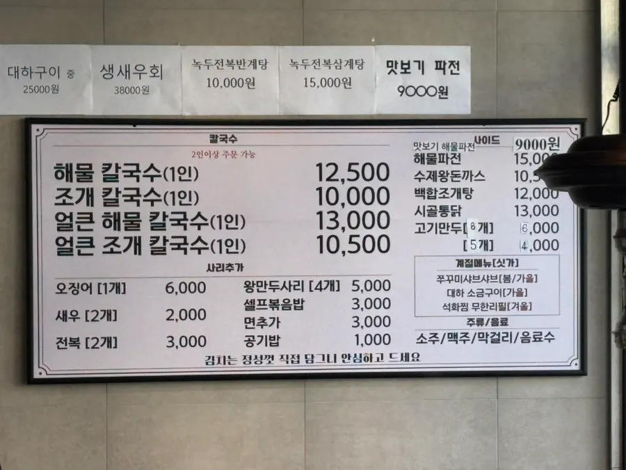 Menu board listing seafood kalguksu and seafood pajeon