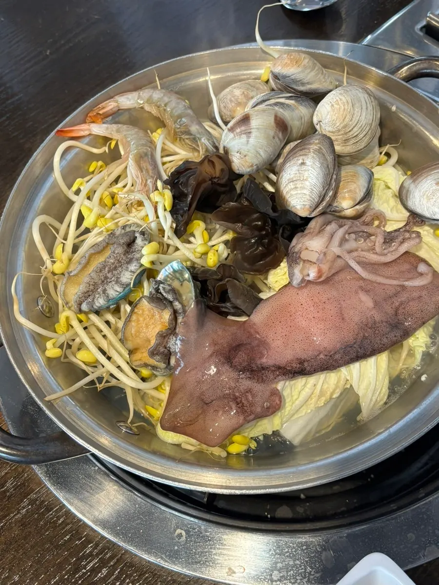 Pot of seafood kalguksu with raw seafood before boiling
