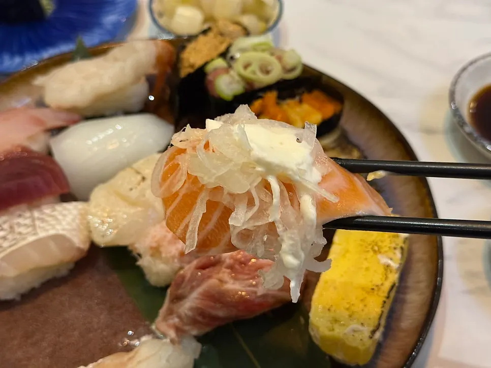 Thick salmon sushi topped with onion