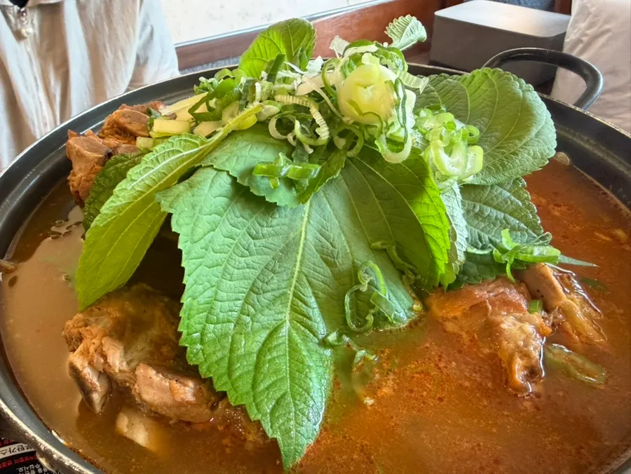Clean broth gamjatang topped with perilla leaves