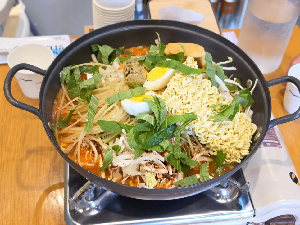 A pot of instant tteokbokki topped with ramyeon noodles, jjolmyeon and boiled egg