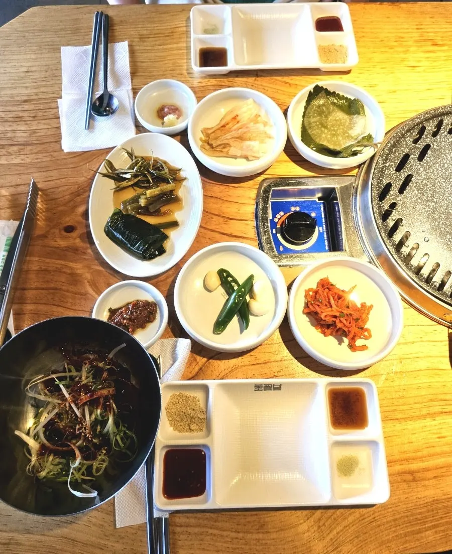 Side dish spread with white kimchi, pickles, and seasoned radish