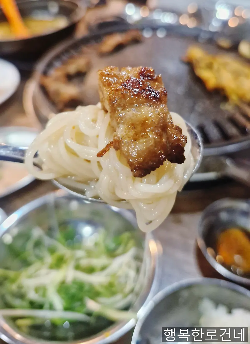 A bite of meat over kimchi noodles