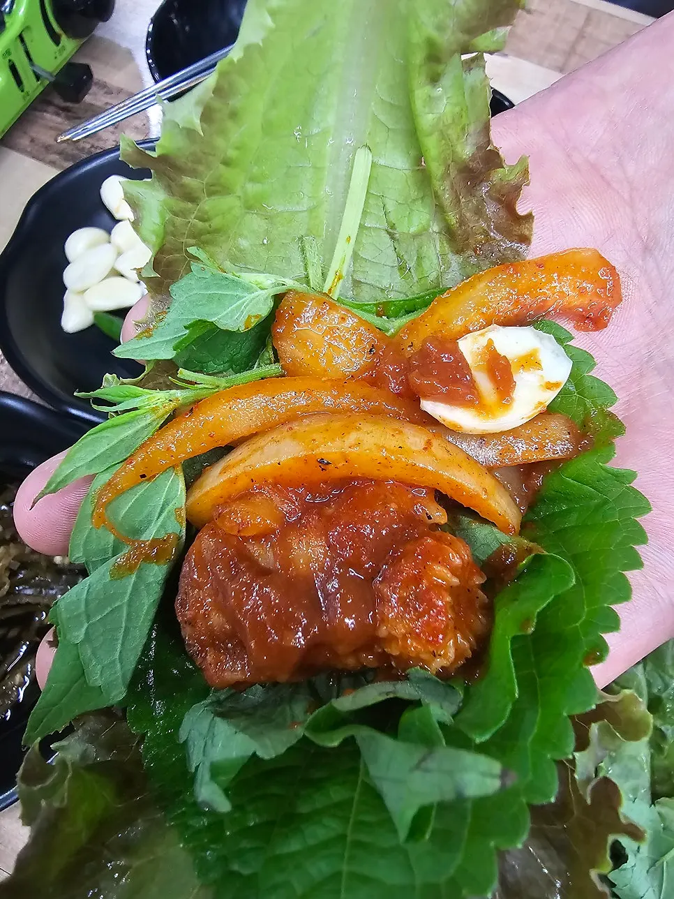 Kkomjangeo wrap topped with onion and mint leaf
