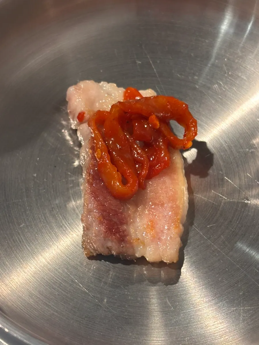 A piece of house-made jeotgal placed on grilled meat