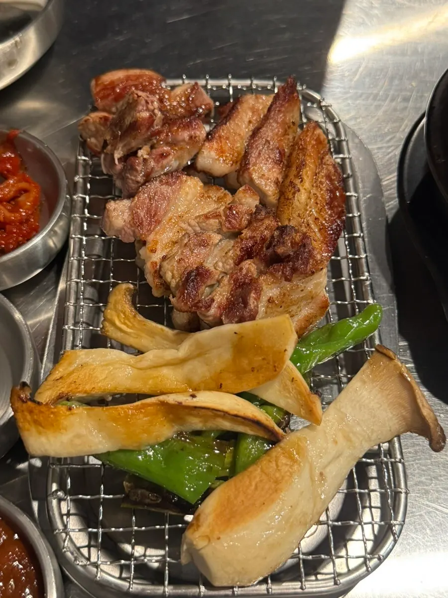 젓가락으로 집어 든 육즙 가득한 생갈비 한 점