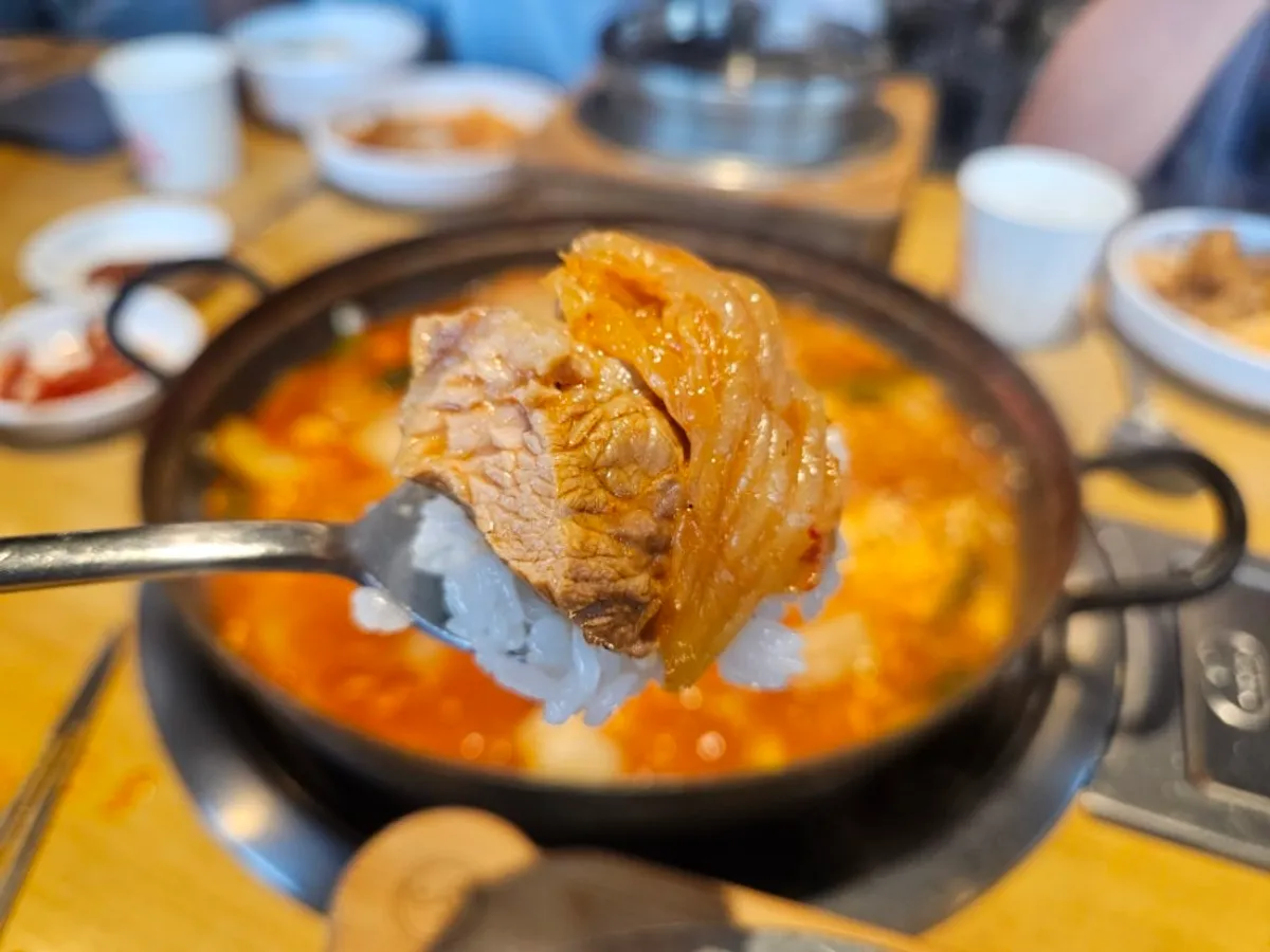 A bite of sotbap topped with kimchi and pork