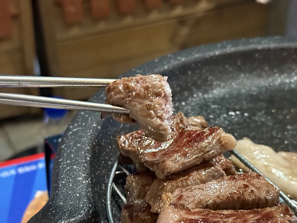 Hanwoo striploin grilling on the outdoor tent table
