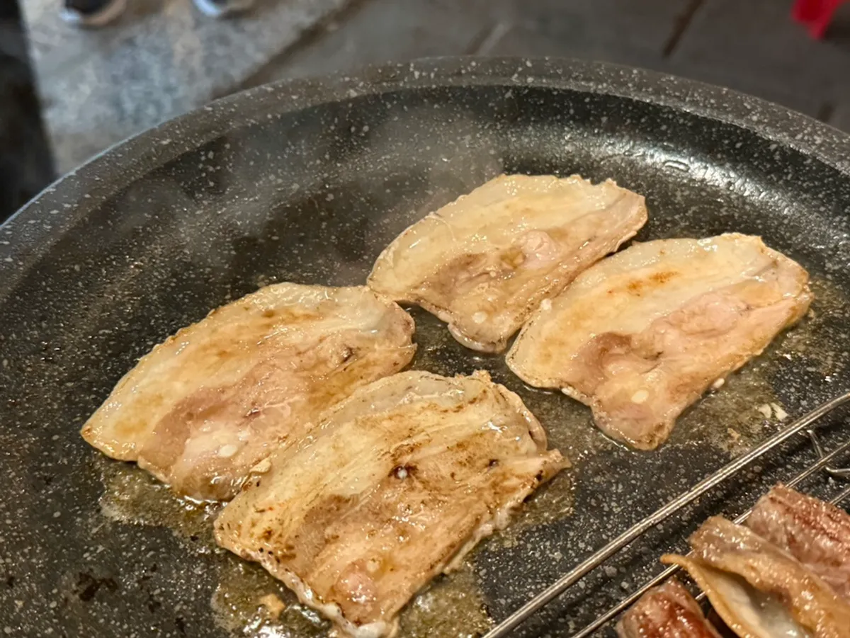 Frozen pork belly grilling to golden brown on the pan