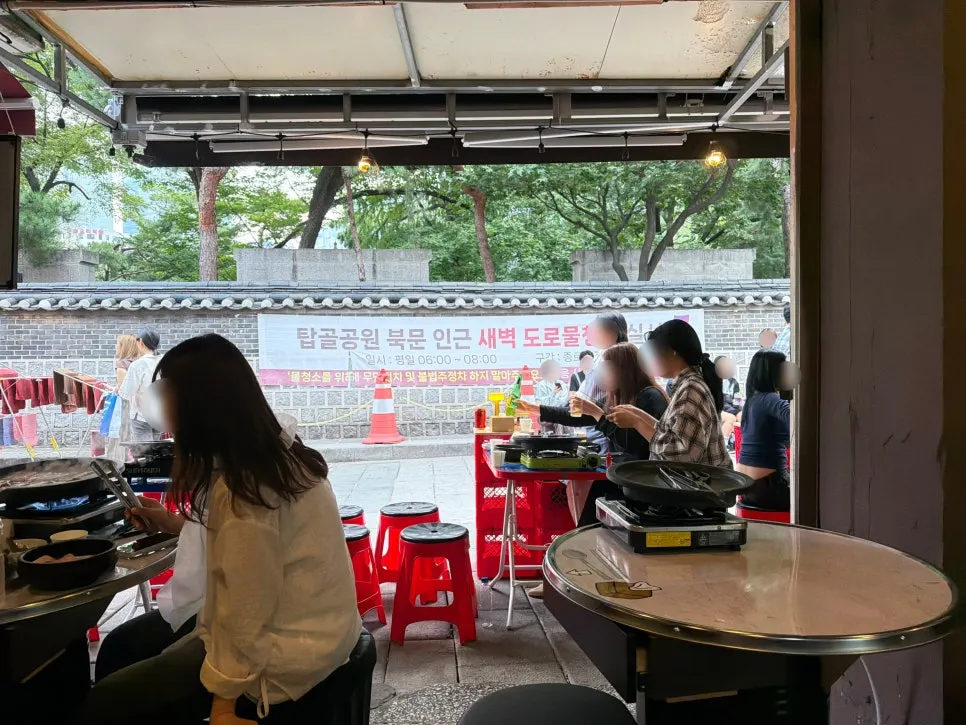 Outdoor seating at Chowon Restaurant next to the Tapgol Park stone wall