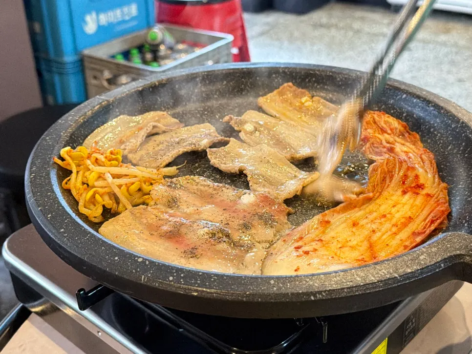 Thinly sliced frozen pork belly cooking on the grill