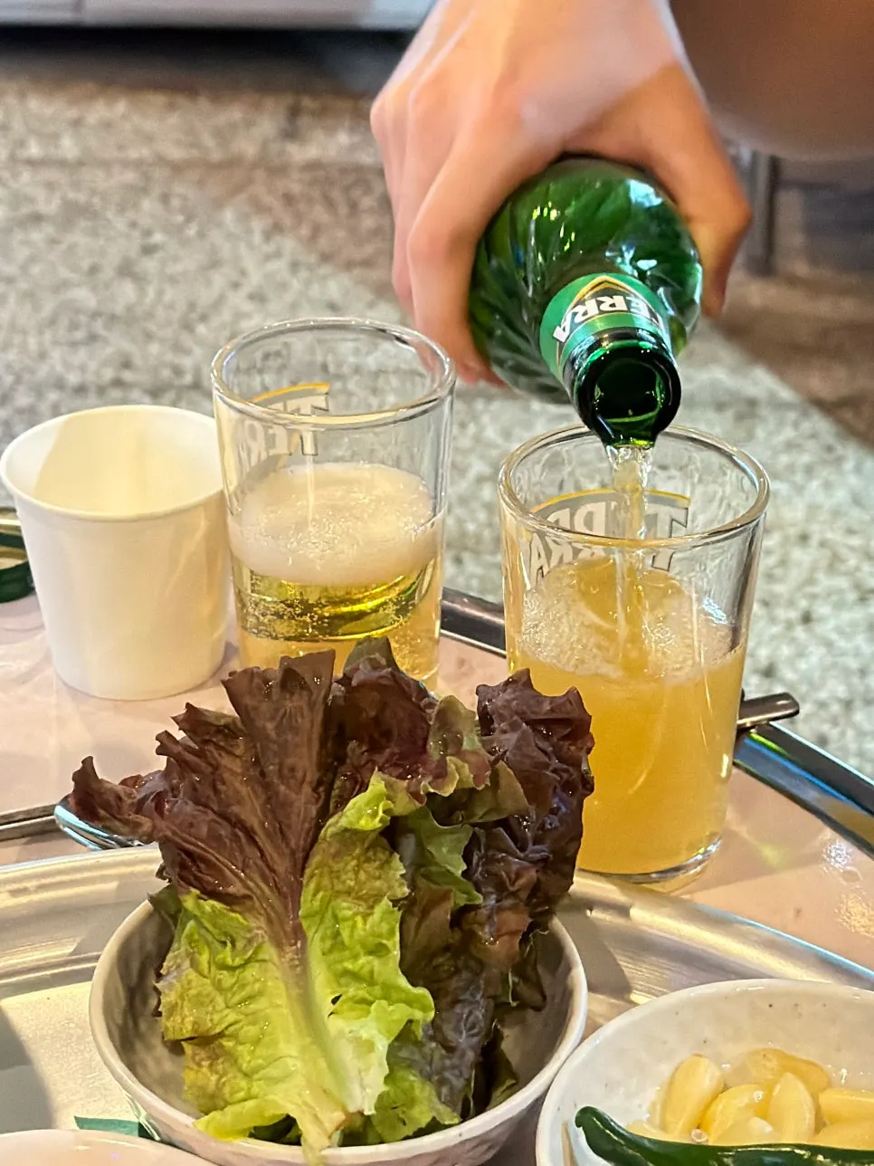 A drink of soju and beer alongside the meat