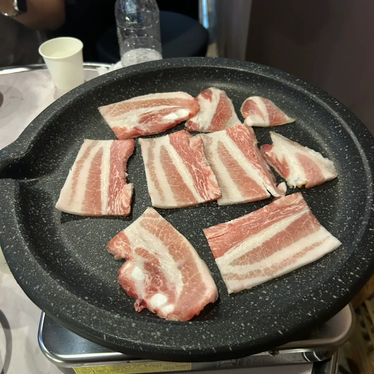 Frozen pork belly placed on the hot grill