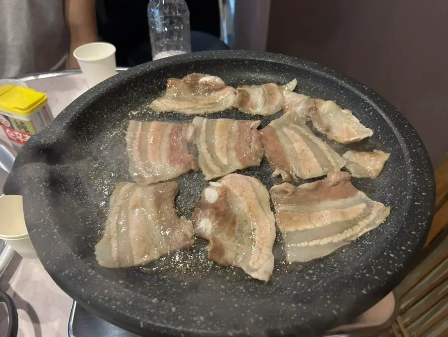 Thin frozen pork belly cooking on the grill