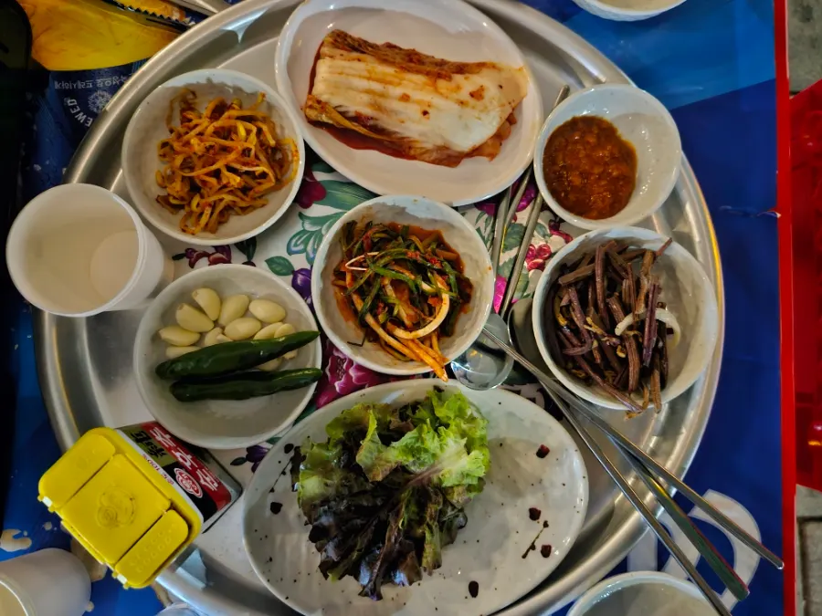Bracken fern, green onion kimchi, and bean sprout banchan set on the outdoor tent table