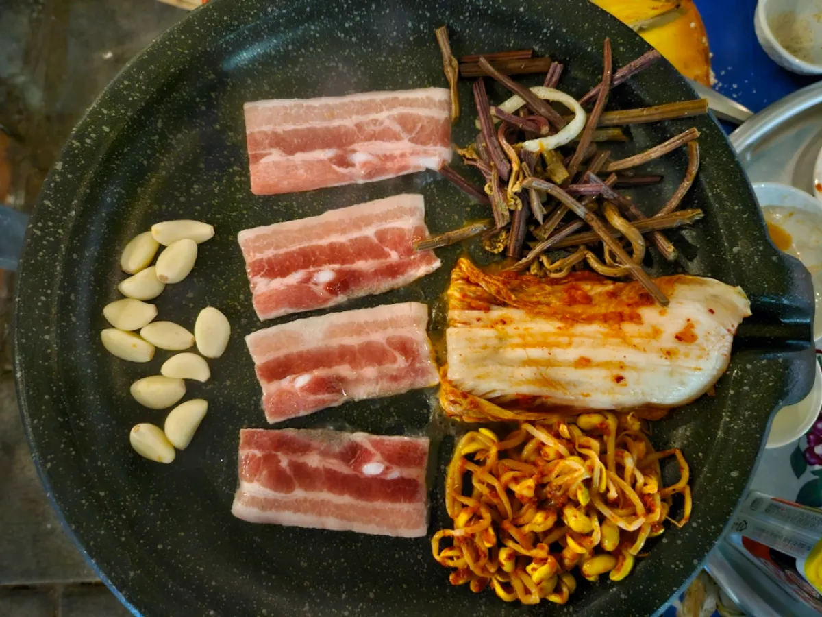 Bracken fern and banchan grilling alongside the pork belly