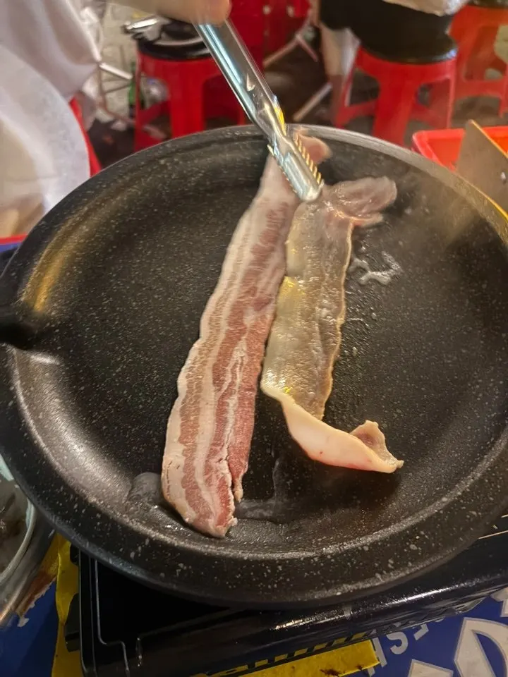돌판 위에서 익어가는 얇은 냉동 삼겹살