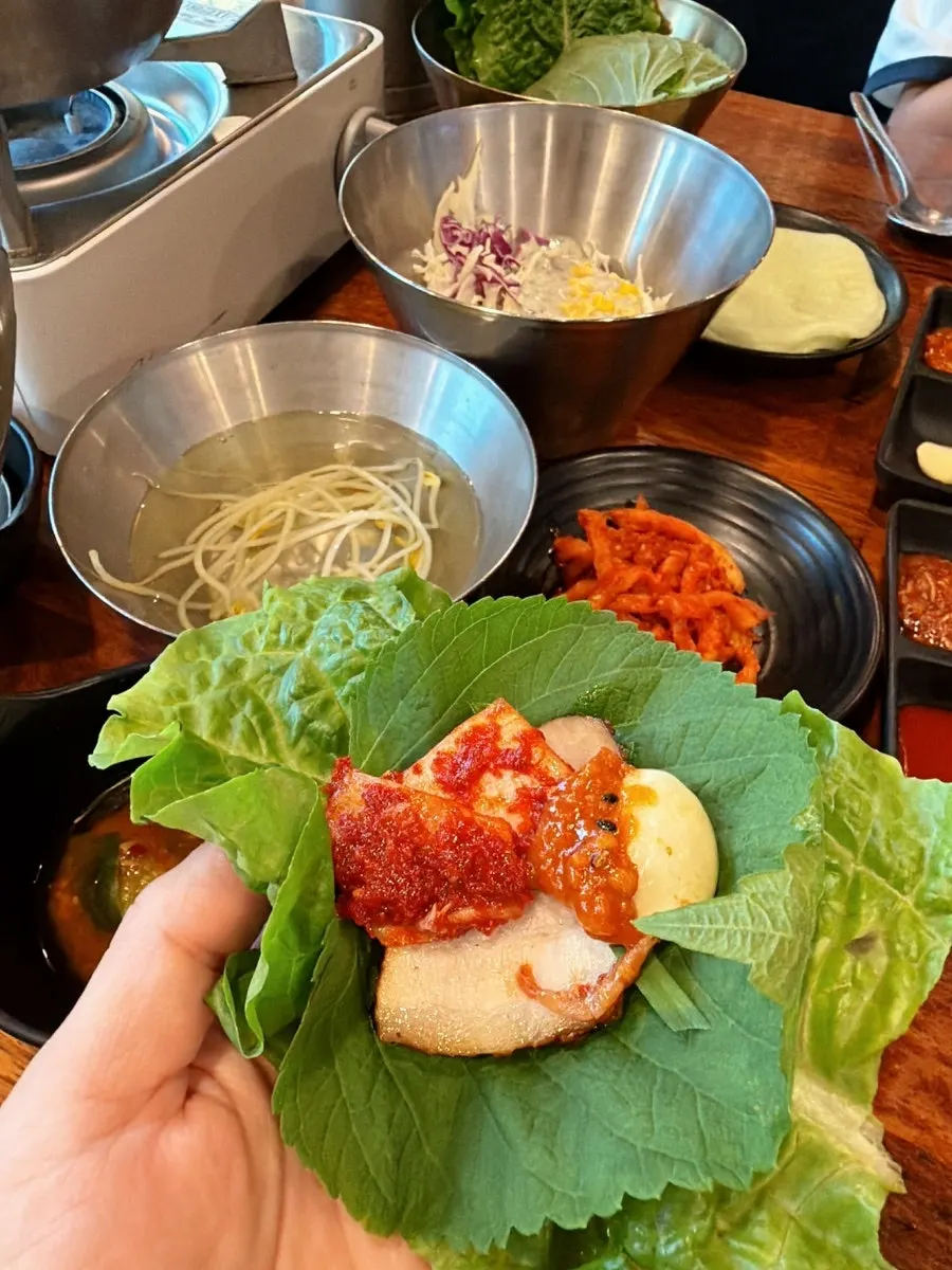 A wrap of bossam meat with kimchi