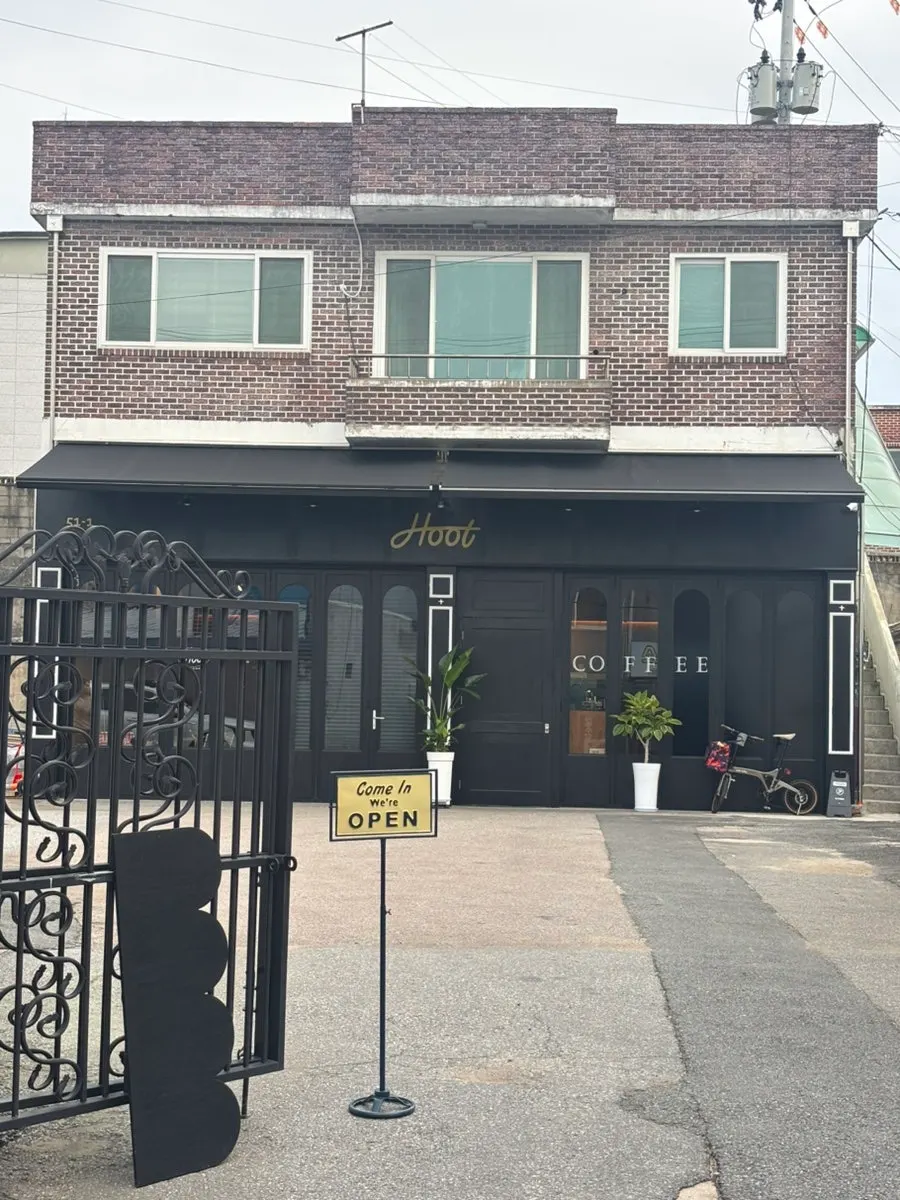 블랙 외관과 입간판이 있는 춘천 명동 카페 훗 전경