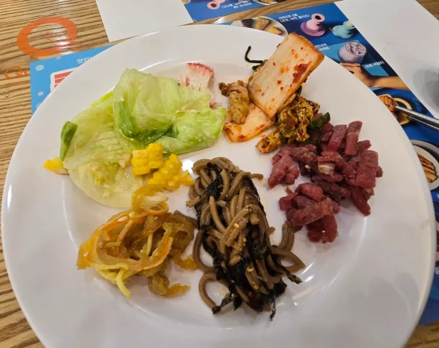 A plate with yukhoe, fresh cabbage kimchi, and buckwheat noodles