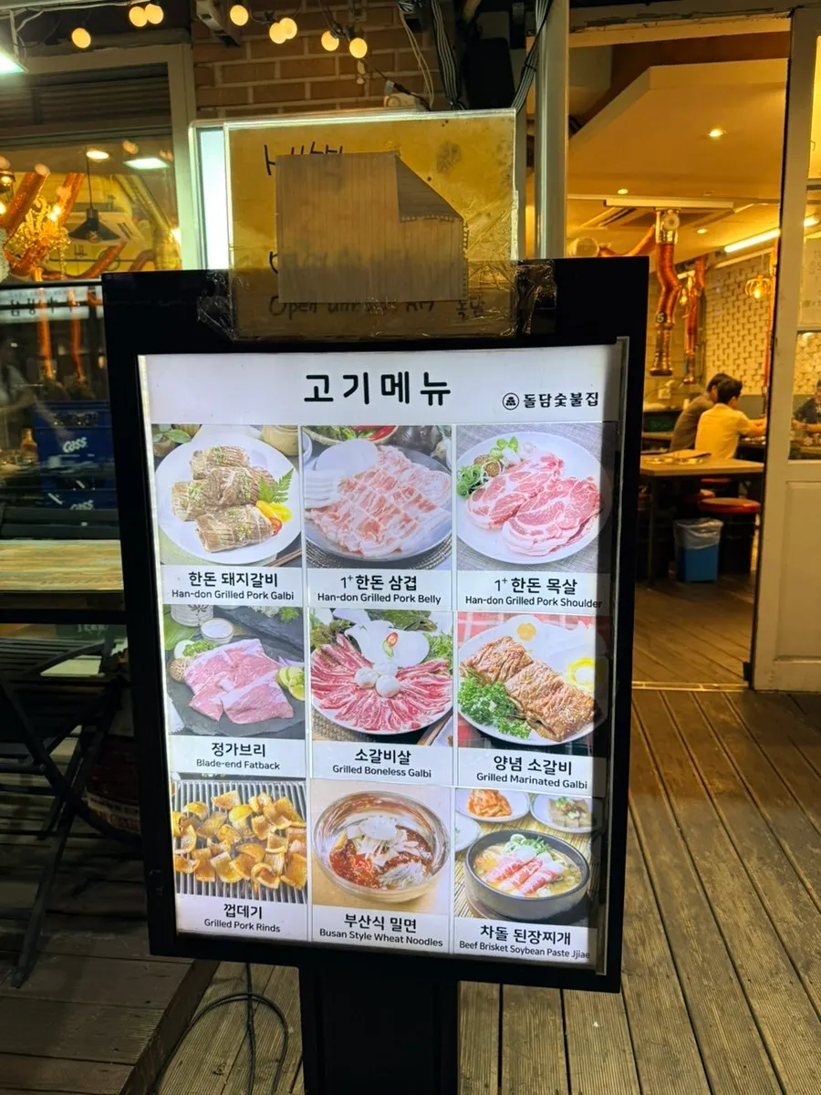 고기메뉴 사진이 실린 돌담숯불집 입간판