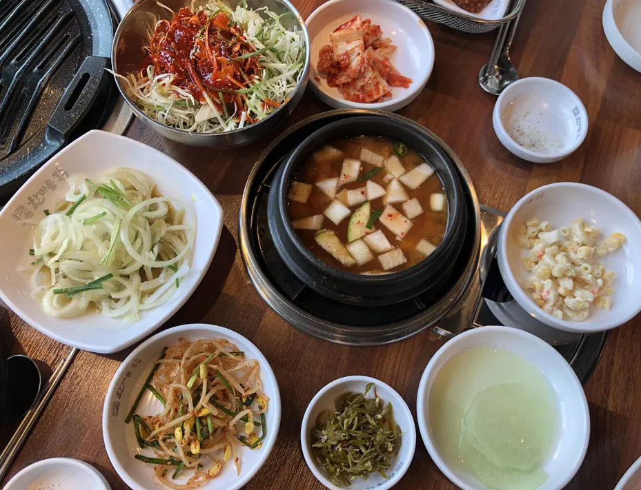 Basic table setting with kimchi, bean sprouts, steamed egg and soybean paste stew