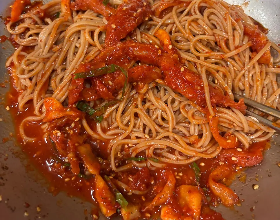 Pollock hoe makguksu piled high with minari and pollock hoe