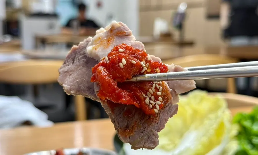 菜包肉上放上明太魚膾與泡菜的樣子