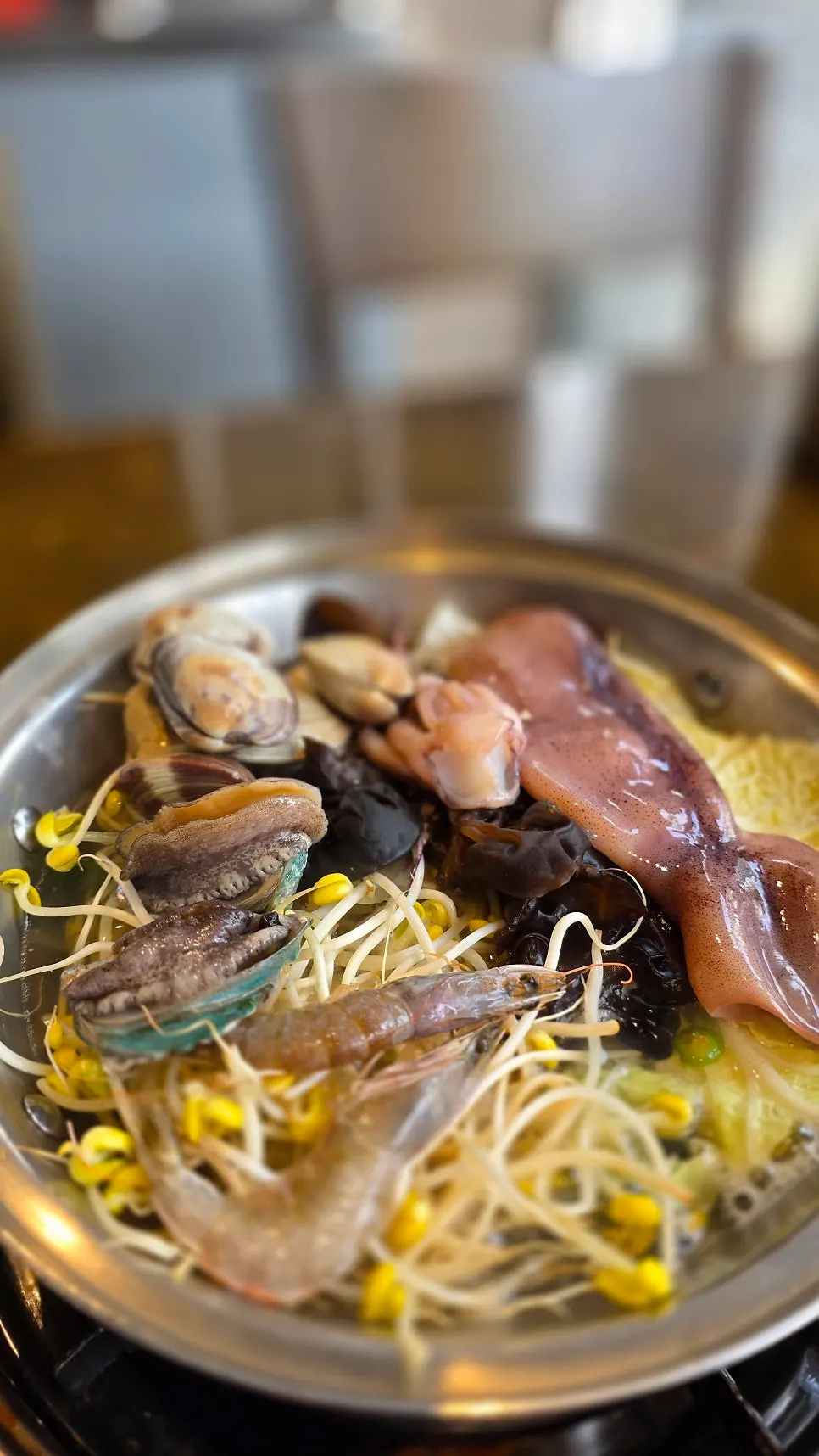 A pot of seafood kalguksu topped with a whole large squid