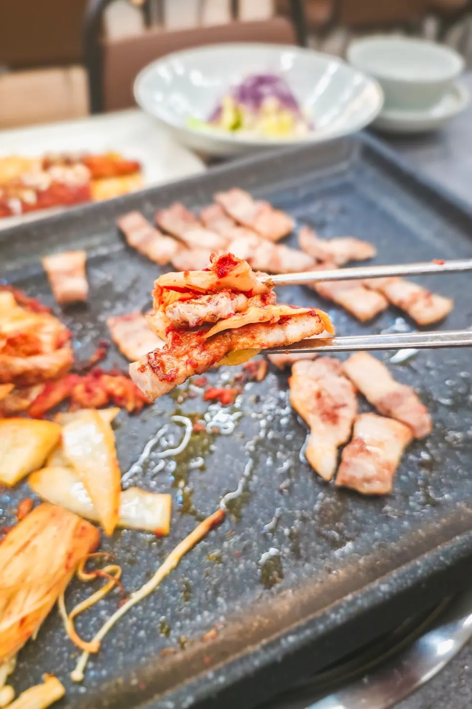 Pork belly and aged kimchi grilling on the stone griddle